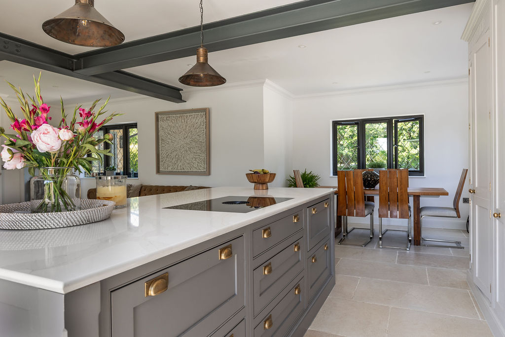 Open-plan kitchen in a rear extension with central island, exposed steel beams and dining area overlooking the garden.